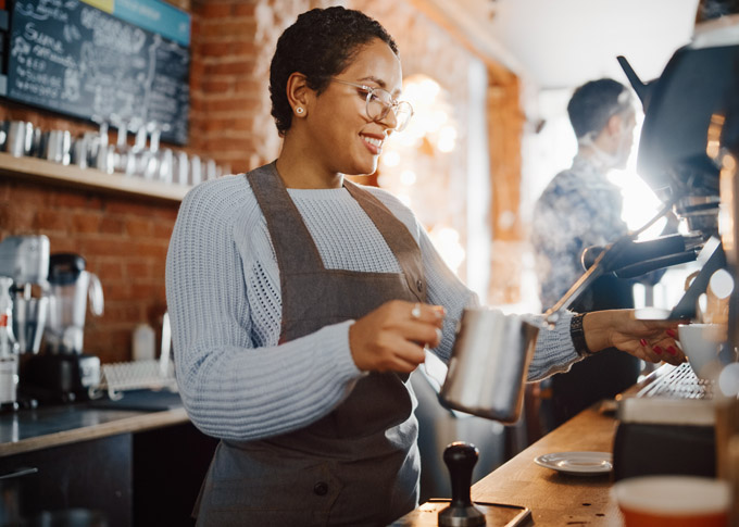 THE SIDINGS HOSTS ITS FIRST-EVER COFFEE FESTIVAL Beautiful Latin American Female Barista with Short Hair and Glasses is Making a Cup of Tasty Cappuccino in Coffee Shop Bar. Portrait of Happy Employee Behind Cozy Loft-Style Cafe Counter.